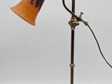 an antique brass table lamp with an orange shade on a white background