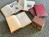 several old books sitting on top of each other on top of a carpet