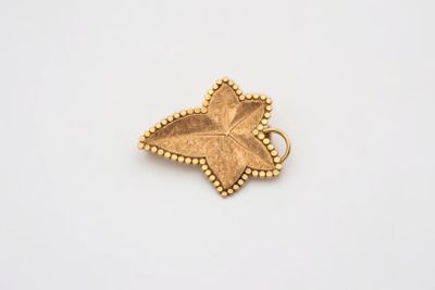 un pendentif en feuille d'or aux bords ornés de perles, sur fond blanc