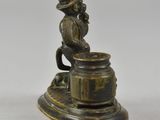 bronze figurine of a man sitting on a barrel with a hat on his head