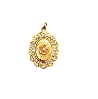 a close up of a gold pendant with a flower on it
