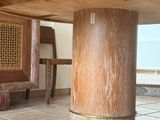 une table en bois avec un piètement en bois et une chaise en bois à l'arrière-plan