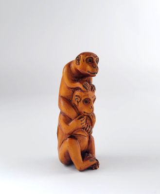 une vieille statue en bois représentant un singe portant un bébé sur le dos