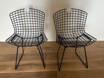 pair of black wire chairs sitting on top of a wooden floor