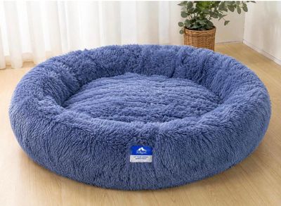 un gros plan sur un panier pour chien bleu posé sur un parquet