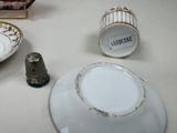 a white plate with gold trim and a silver thimble next to it