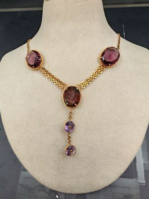 Le collier est composé d'or et de pierres violettes.