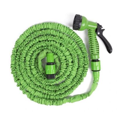 un tuyau vert muni d'un pistolet pulvérisateur, posé sur une surface blanche