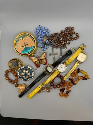 a lot of jewelry on a table with a watch and a pen