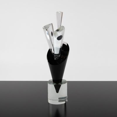 un vase en verre contenant trois couteaux, posé sur une table