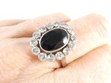 a woman ' s hand holding a ring with a black stone on it