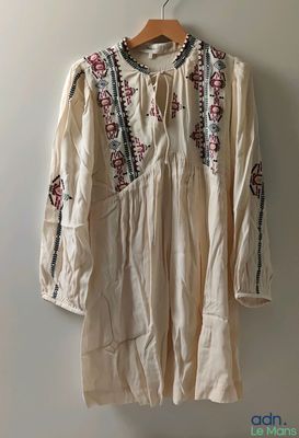 une photo d'une chemise suspendue à un mur à l'aide d'un cintre en bois
