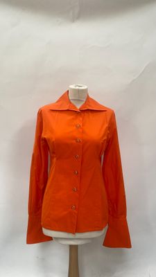 an orange jacket on a mannequin stand against a white backdrop