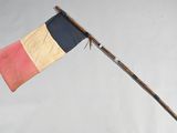 un vieux mât en bois surmonté d'un drapeau, posé sur une surface blanche