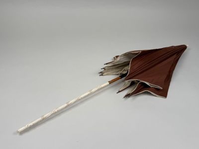 brown umbrella with white handle on a white surface