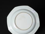 a white plate with a gold rim on a black surface