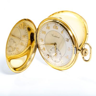 une montre de poche en or posée sur une surface blanche
