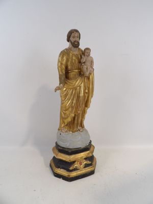 une statue de Jésus tenant un enfant dans ses bras, posée sur un socle