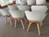 several white chairs with wooden legs in a room with a large window