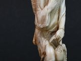 an antique carved ivory figurine of a man carrying a basket