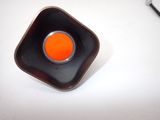 a small orange object in a black bowl on a white table