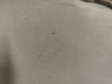 a close up of a bed with a white comforter and a brown pillow