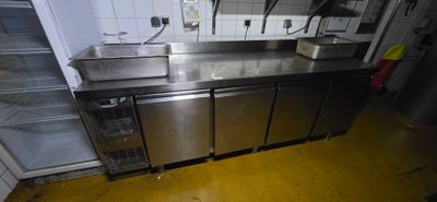 a stainless steel counter top in a kitchen with a refrigerator