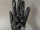 black leather gloves on a person ' s hand against a gray wall
