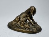 statue en bronze représentant un chien couché sur un rocher avec deux chiots