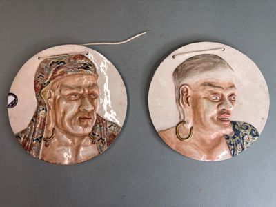 une paire de portraits en céramique représentant un homme et une femme, accrochés au mur