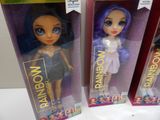 three dolls of different colors are in boxes on a table