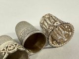 three antique silver thimbles are sitting on a white surface