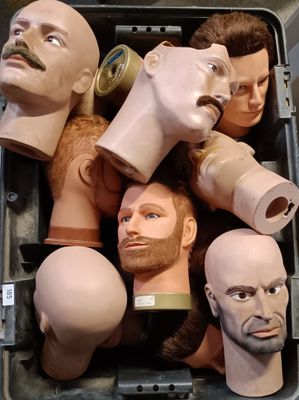 many mannequin heads in a box with a man ' s face