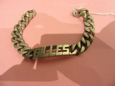 a metal bracelet with a name on it on a pink surface