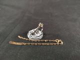a close up of a gold chain with a small boat on it