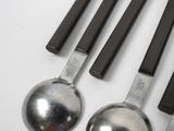 several spoons and spoon rest on a white surface with black handles