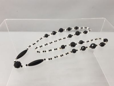 un collier de perles noires et blanches présenté dans une vitrine transparente