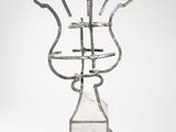 une photo d'une sculpture métallique représentant un vase posé sur un socle en bois