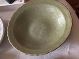 a green bowl sitting on top of a table next to a plate
