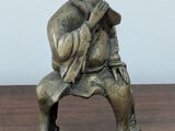 a small statue of a man sitting on a bench