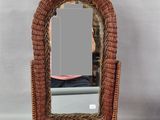 une chaise en osier avec un miroir fixé au dossier