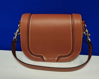 a brown leather cross body bag sitting on top of a table