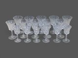 six clear wine glasses are lined up in a row on a gray surface