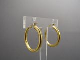 a close up of a pair of gold hoop earrings on a clear stand