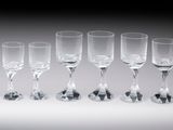 six empty wine glasses lined up in a row on a white surface
