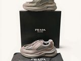 baskets Prada grises et blanches avec leur boîte, sur fond blanc
