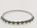 un gros plan d'un bracelet orné de pierres vertes sur fond blanc