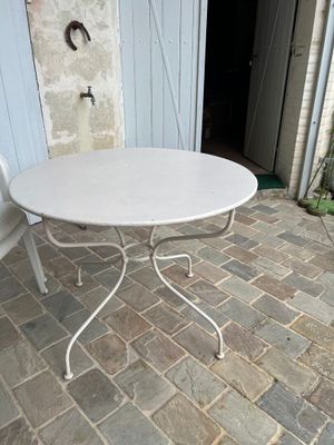 une table blanche et deux chaises sur une terrasse en pierre