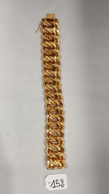 gros plan d'un bracelet en chaîne en or sur une surface blanche