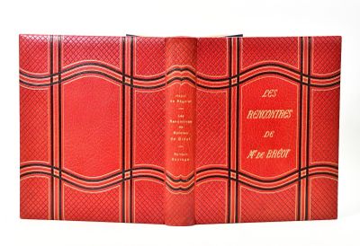 an old book with a red cover sitting on top of a white table